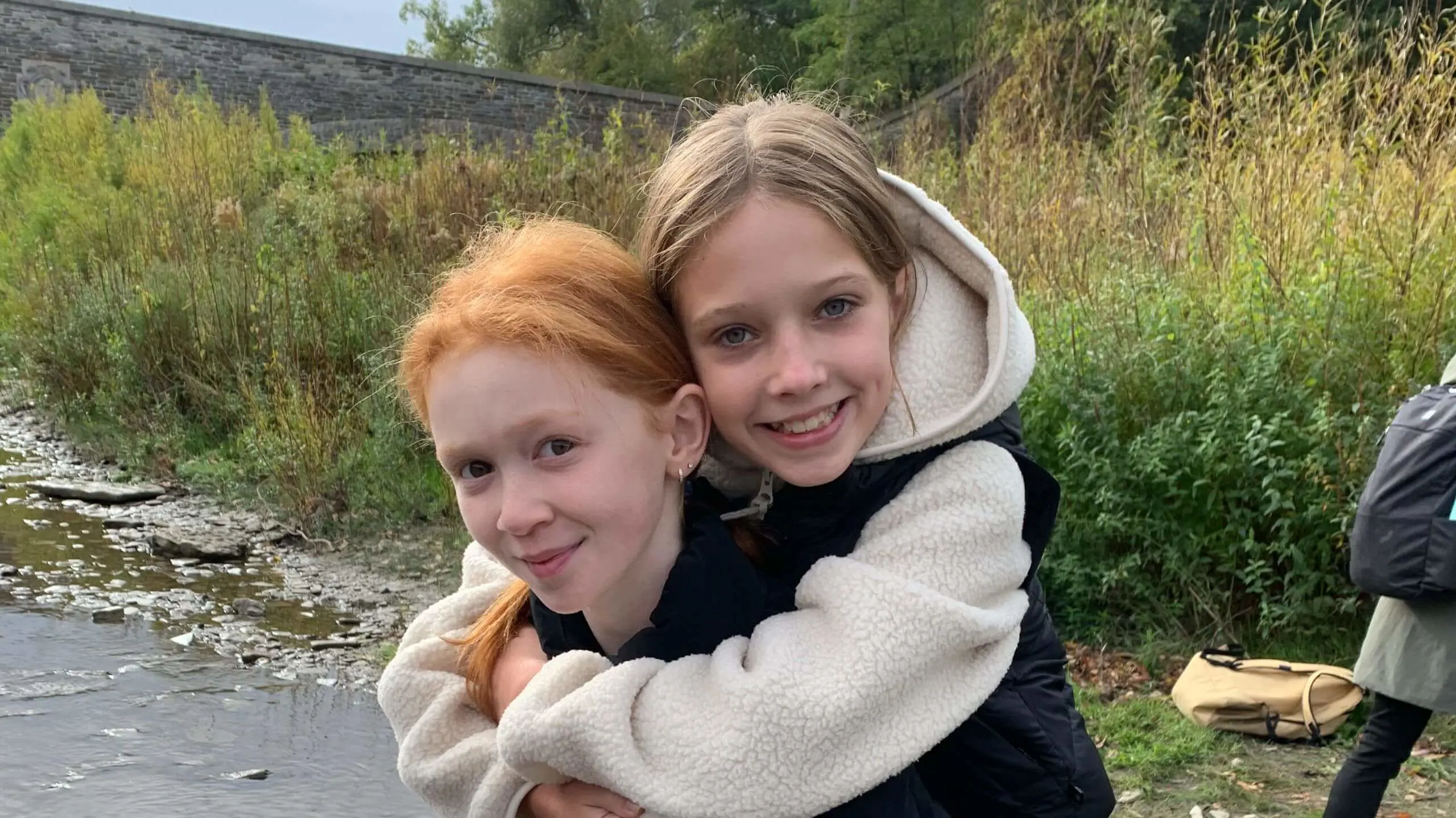 Linden school student carries their friend over a stream.