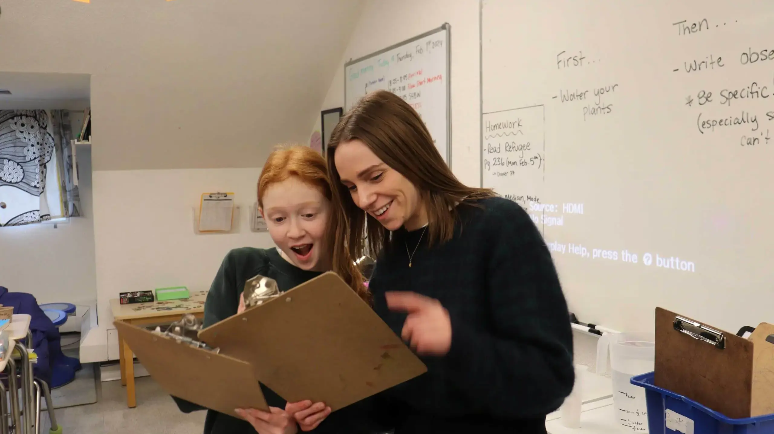 Student and teacher looking excitedly at classwork together.